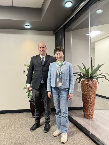 RCIC Cellia Xiao posing with a criminal defense lawyer in an office setting. The two are standing together, smiling in front of a potted plant