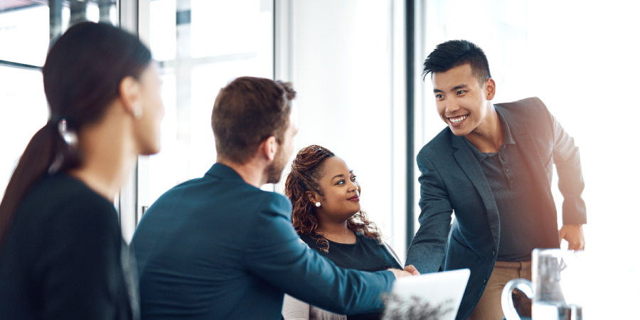 A group of professionals in a business meeting, with one person shaking hands, symbolizing networking and collaboration for the Canada Startup Visa process.