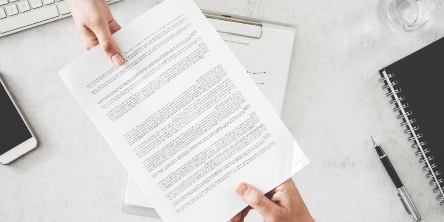 a close-up of two individuals exchanging an official document, symbolizing the process of applying for an open work permit for startup entrepreneurs in canada