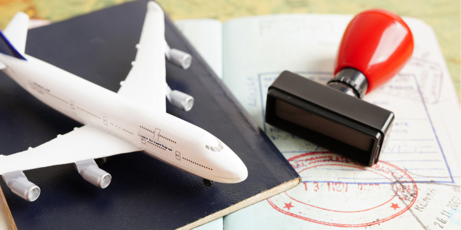 A model airplane, passport, and visa stamp on travel documents, symbolizing the Canada Startup Visa process and international business travel.