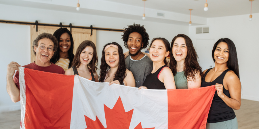 diverse group smiling and holding canada flag after successful immigration