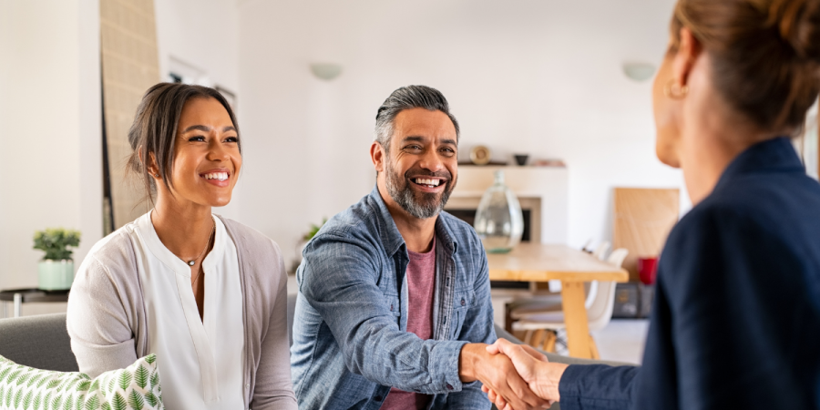 couple smiling and shaking hands with a consultant in a home setting