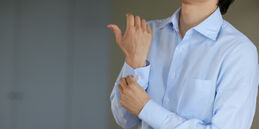man preparing for immigration interview by buttoning up his shirt