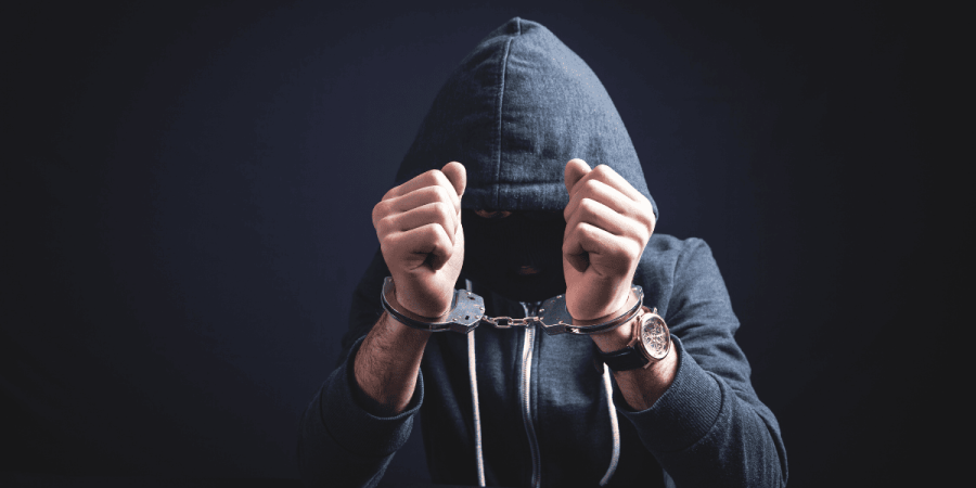 immigration myths linking immigrants to crime shown with hooded man in cuffs