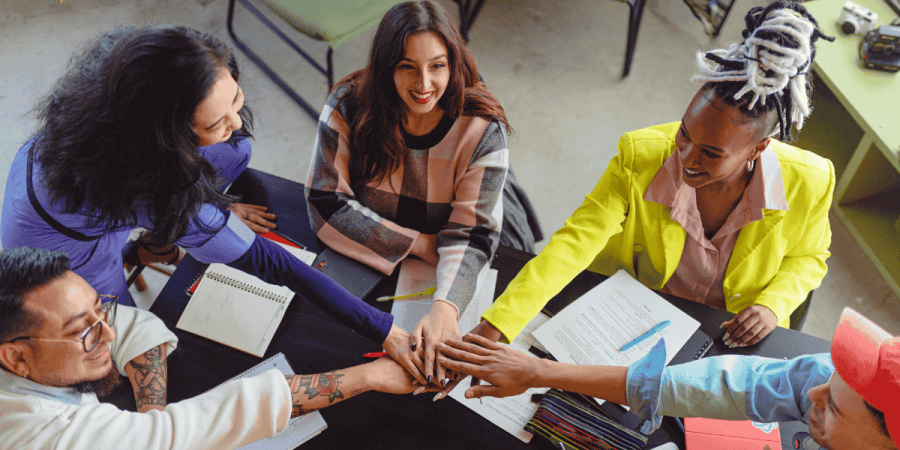 diverse team joining hands in office showing teamwork in work culture