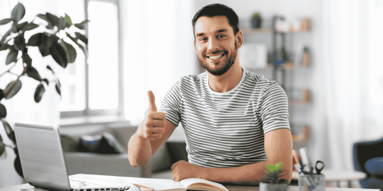 happy man working on laptop showing thumbs up for freelance immigration
