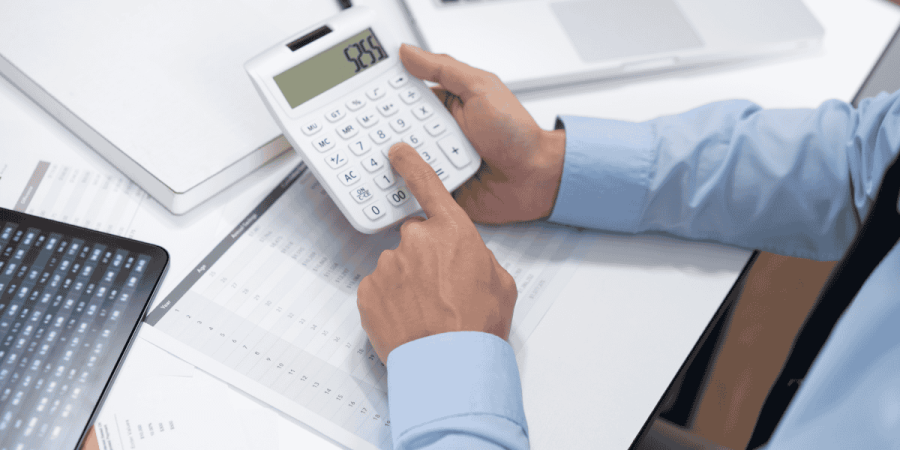 person using calculator and documents to estimate cost of studying and living expenses